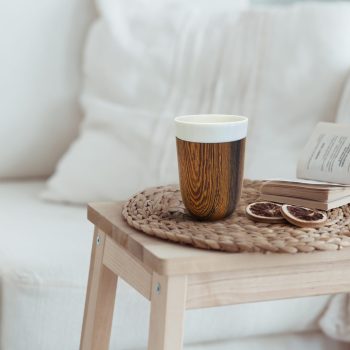 Still life interior details, cup of coffee and a book near white cozy chair